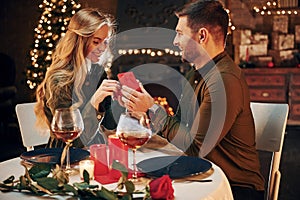 Man proposing a beautiful woman to marry him in an elegant restaurant. Young lovely couple have romantic dinner indoors together