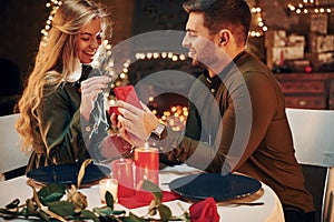 Man proposing a beautiful woman to marry him in an elegant restaurant. Young lovely couple have romantic dinner indoors together