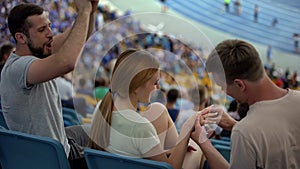 Man proposing marriage to girl at stadium, wearing engagement ring, romantic