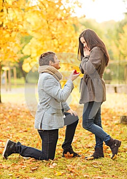 Man proposing to a woman in the autumn park