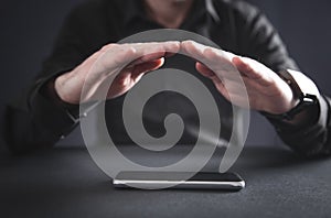 Man with protect gesture. Smartphone on the desk