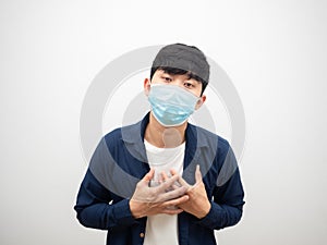 Man with protect mask touch his heart feel bad and sick looking at camera on isolated white