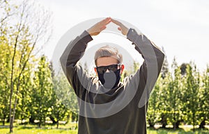 Man in a protective black mask making home sign in a city park. Copy space. Concept symbol home made by hands on the