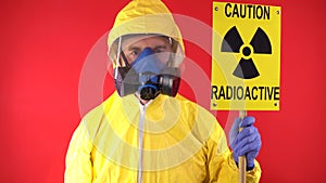 A man in a protective chemical suit, in a protective mask with the poster "Caution radiation". Radiation hazard concept