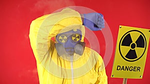 Man in protective chemical suit, protective mask with a poster Caution radiation on a red background. Radiation concept