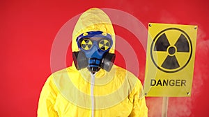 A man in a protective chemical suit, in a protective mask with a radiation poster. Isolate, studio shooting. Radiation