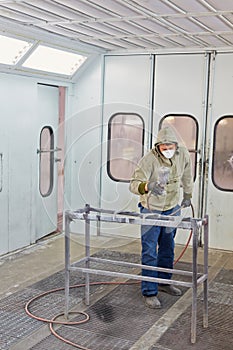 Man in protective clothes works in paint-spraying booth