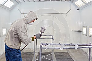 Man in protective clothes works in paint-spraying booth