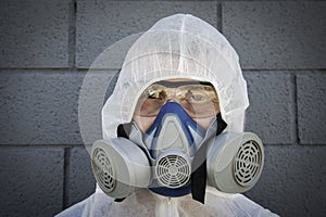 Man in protective clothing and a gas mask on an urban gray background - Worker ready for disinfection and decontamination for