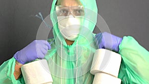 A man in a protective coat with a hood, a gauze mask and glasses on his face. Puts toilet paper rolls on the neck. Virus