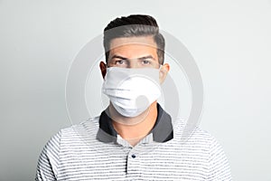 Man in protective face mask on light grey background
