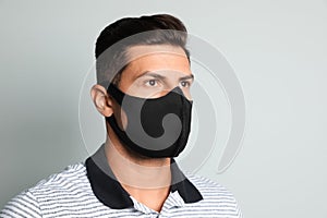 Man in protective face mask on light grey background