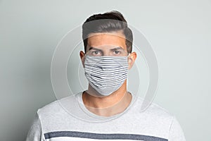 Man in protective face mask on light grey background