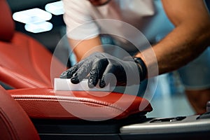 Man in protective gloves cleans a leather armrest