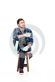 man in protective gloves sitting on chair with paint roller