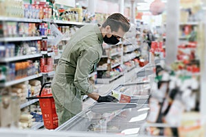 A man in a protective mask selects products in a supermarket