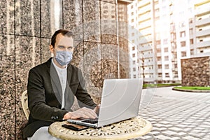 Man in protective mask is working with laptop