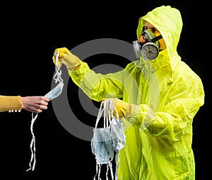 Man in protective respirator and gloves giving mask to a woman for protection against viruses and infections over black background