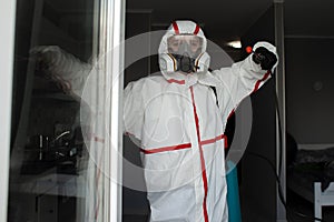 Man in a protective suit cleans the apartment of infections with a chemical agent, sanitary work in the apartment