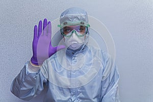 A man in a protective suit demonstrates sign STOP . Personal protection against viruses - health and medicine concept