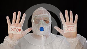 Man in protective suit and gloves showing sign stop coronavirus. Bio engineer in safety costume showing stop covid-19