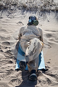 man in protective suit, mask on sand