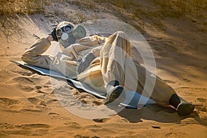 Man in protective suit, mask on sand