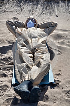 Man in protective suit, mask on sand