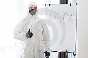 Man in protective suit, medical mask, goggles with finger up. Isolated in studio. antigas mask with glasses at white