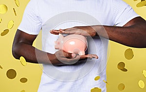 Man protects his piggy bank. concept of savings. yellow background