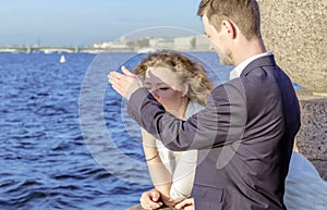 Man protects his woman`s eyes from the rays of the evening sun