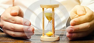 Man protects the hourglass. Concept of saving time and money. Time management. Planning work. Reduced cost and bureaucratic burden