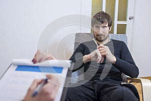 A man at a psychotherapist, sitting in a chair, talks about his problems. Healthcare concept of a professional psychologist doctor
