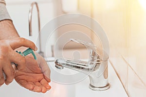 A man in a public place washes his hands in the sink. Squeezing antibacterial hand soap. Precautions and protection for