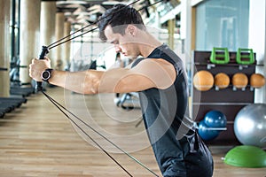 Man pulling cables. Handsome athlete male lifting up and push up on sling to maintain muscle at gym health club.