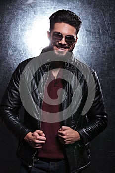 Man pulling on his leather jacket and smiles