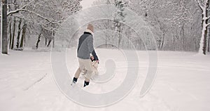 Man pulling his wife on sledge in winter forest