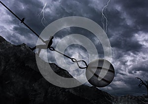 Man Pulling Uphill a big rock with metal chain in a bad dramatic weather