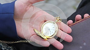 Man pulls out of his pocket vintage pocketwatch on a chain and looking time