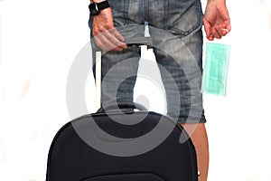 A man pulls a suitcase from the back and holds a medical mask in his hand