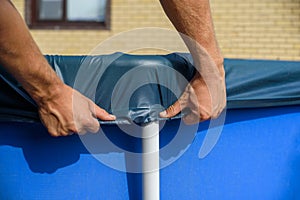 A man pulls up an cover over a home swimming pool.