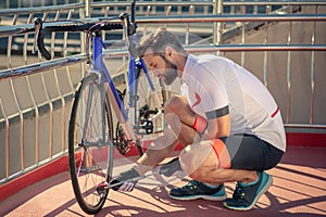 Man with pump crouched near bicycle wheel