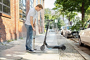 Man Pumping Air Into Tire On E-Scooter