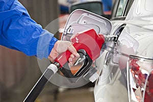 Man Pumping Gasoline Into Silver Car With Red Fuel Nozzle