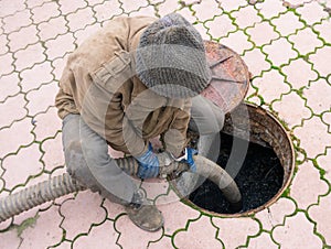 Man pumping sewage from the hole