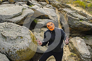 Man in a pumpkin mask in the mountains.