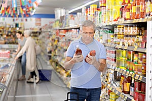 Man purchaser choosing tomato juice in big supermarket