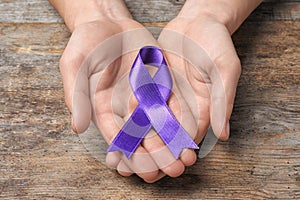 Man with purple awareness ribbon on wooden background
