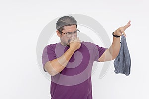 A man in a purple shirt pinches his nose and gestures with disdain at a foul-smelling gray underwear photo