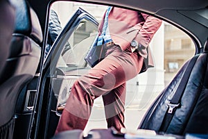 Man in purple suit getting in the luxury limo